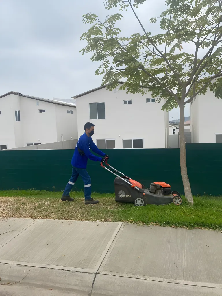 Jardinero de SolutionPlus podando setos en una urbanización