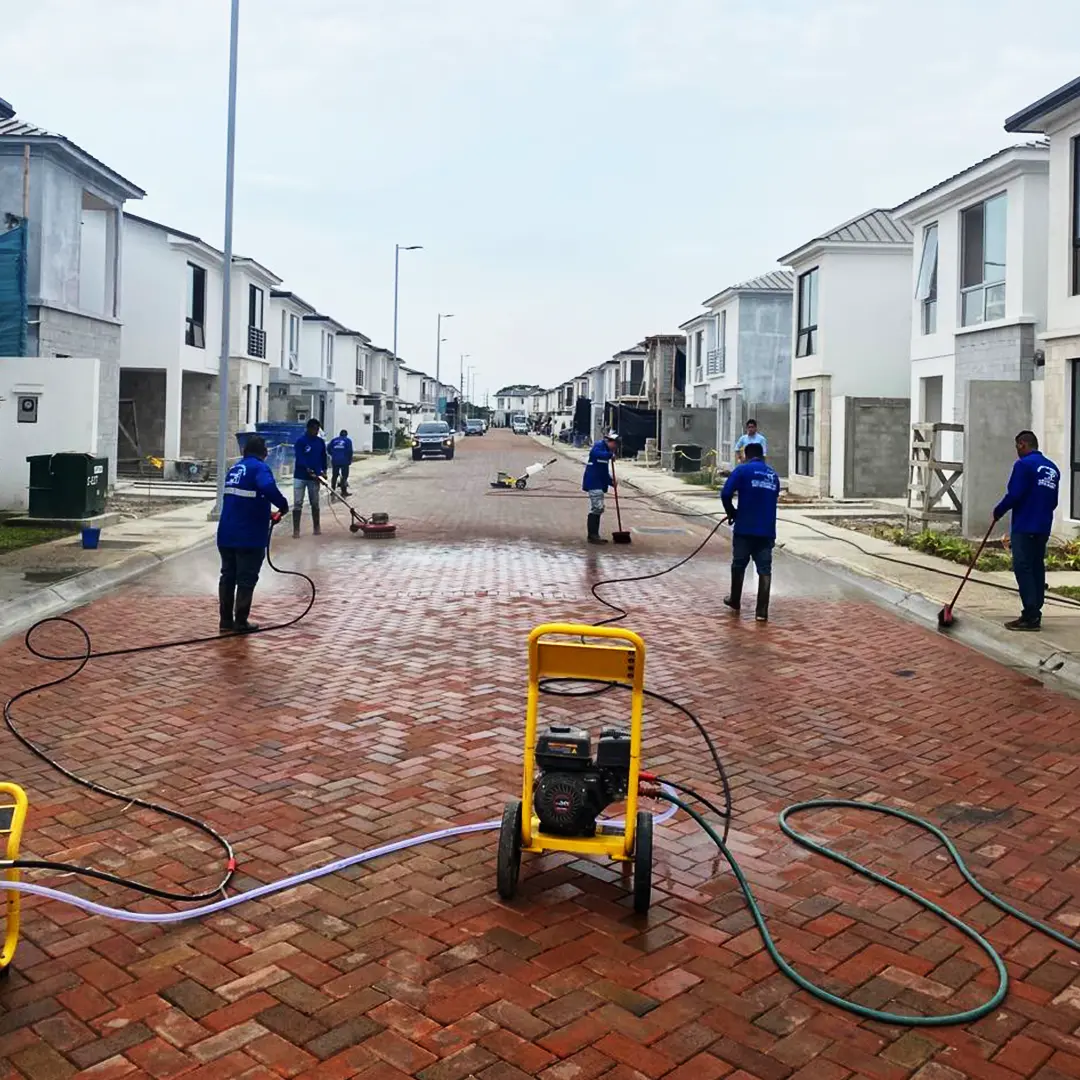 Cuadrilla de SolutionPlus lavando con hidrolavadoras la calle adoquinada de una urbanización