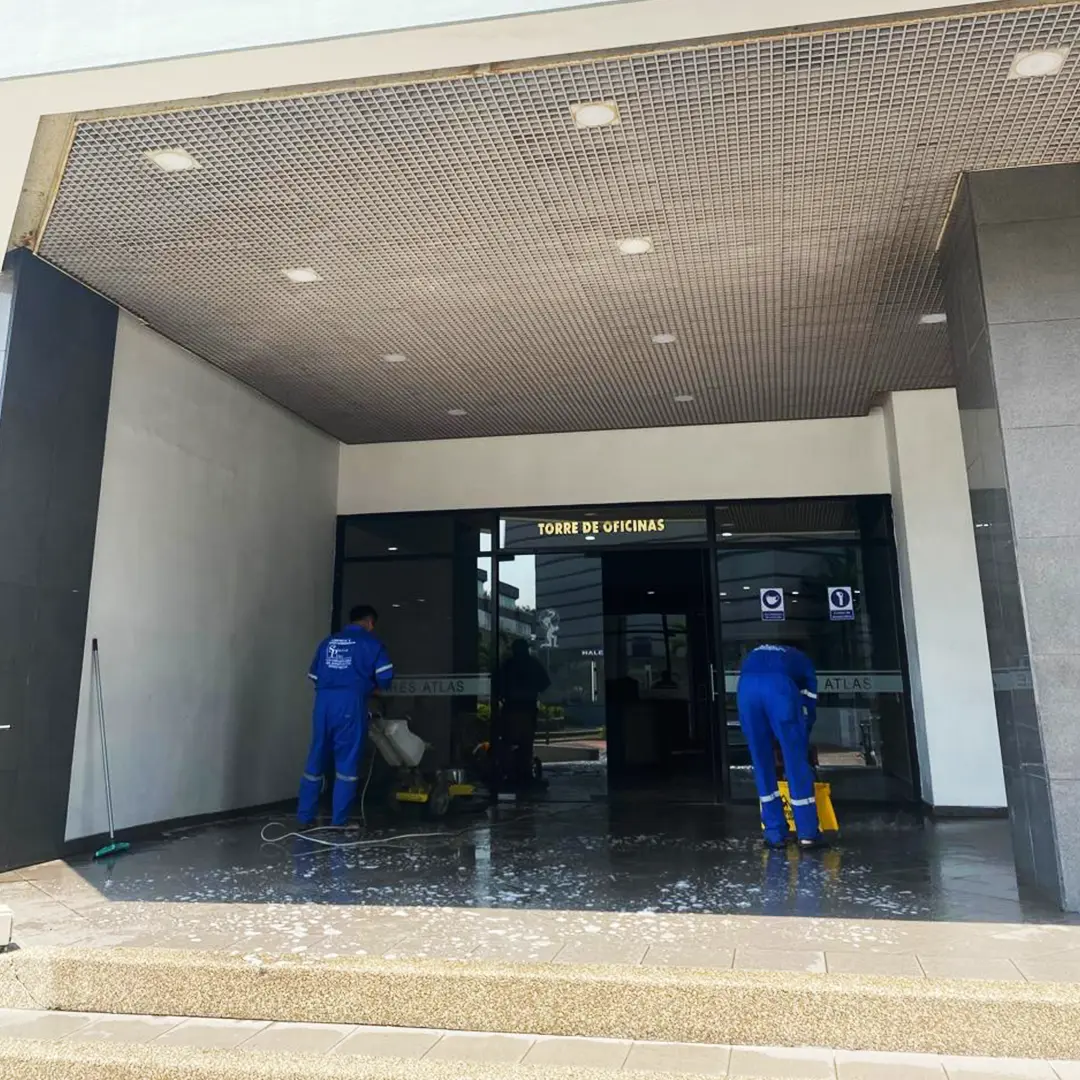 Personal de SolutionPlus puliendo el piso de entrada de una torre de oficinas