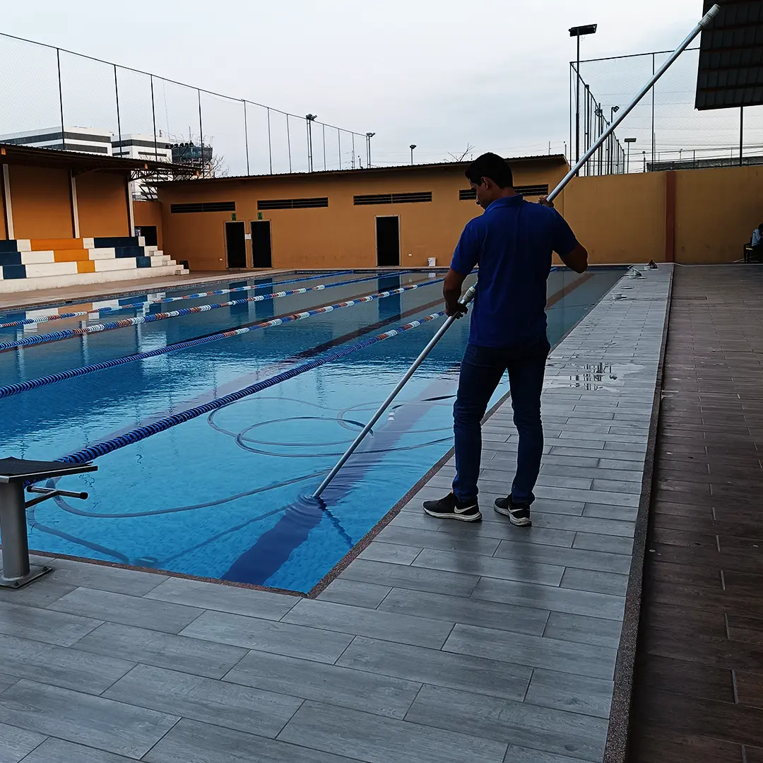 Trabajador de SolutionPlus limpiando una piscina semiolímpica con pértiga
