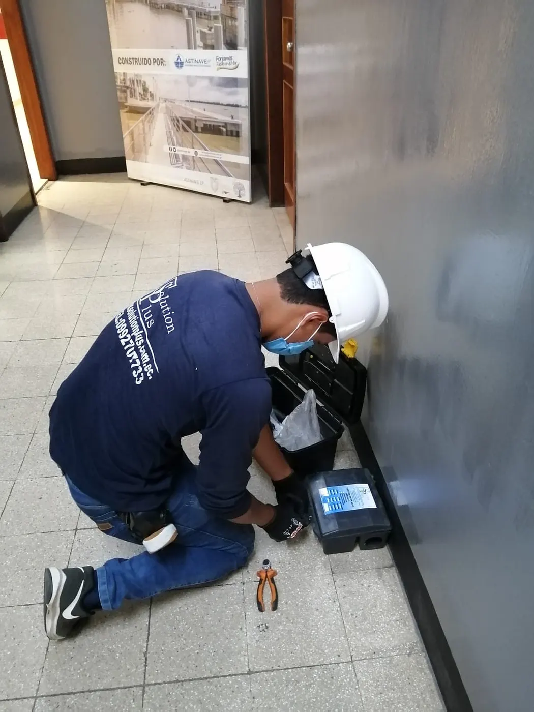 Técnico de SolutionPlus instalando una estación de cebo en el interior de un edificio