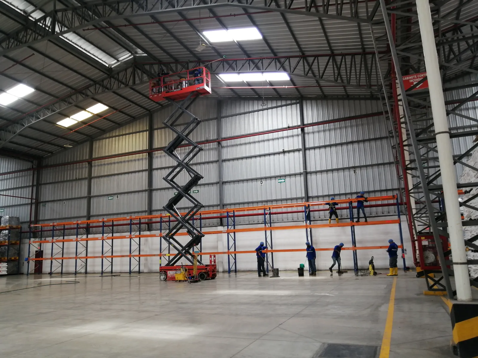 Cuadrilla de SolutionPlus limpiando una nave industrial con plataforma elevadora