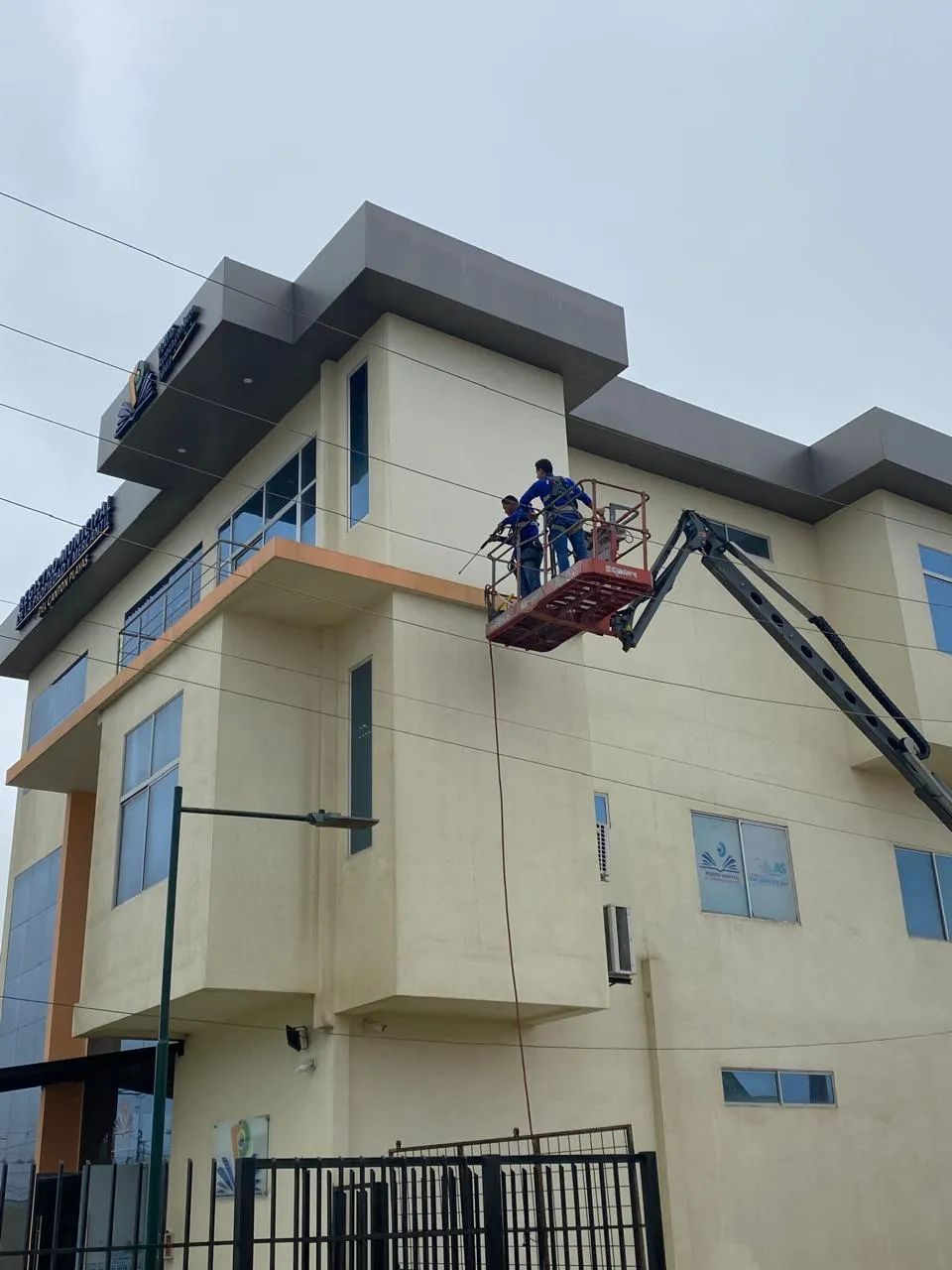 Personal de SolutionPlus limpiando la fachada de un edificio municipal desde un brazo articulado