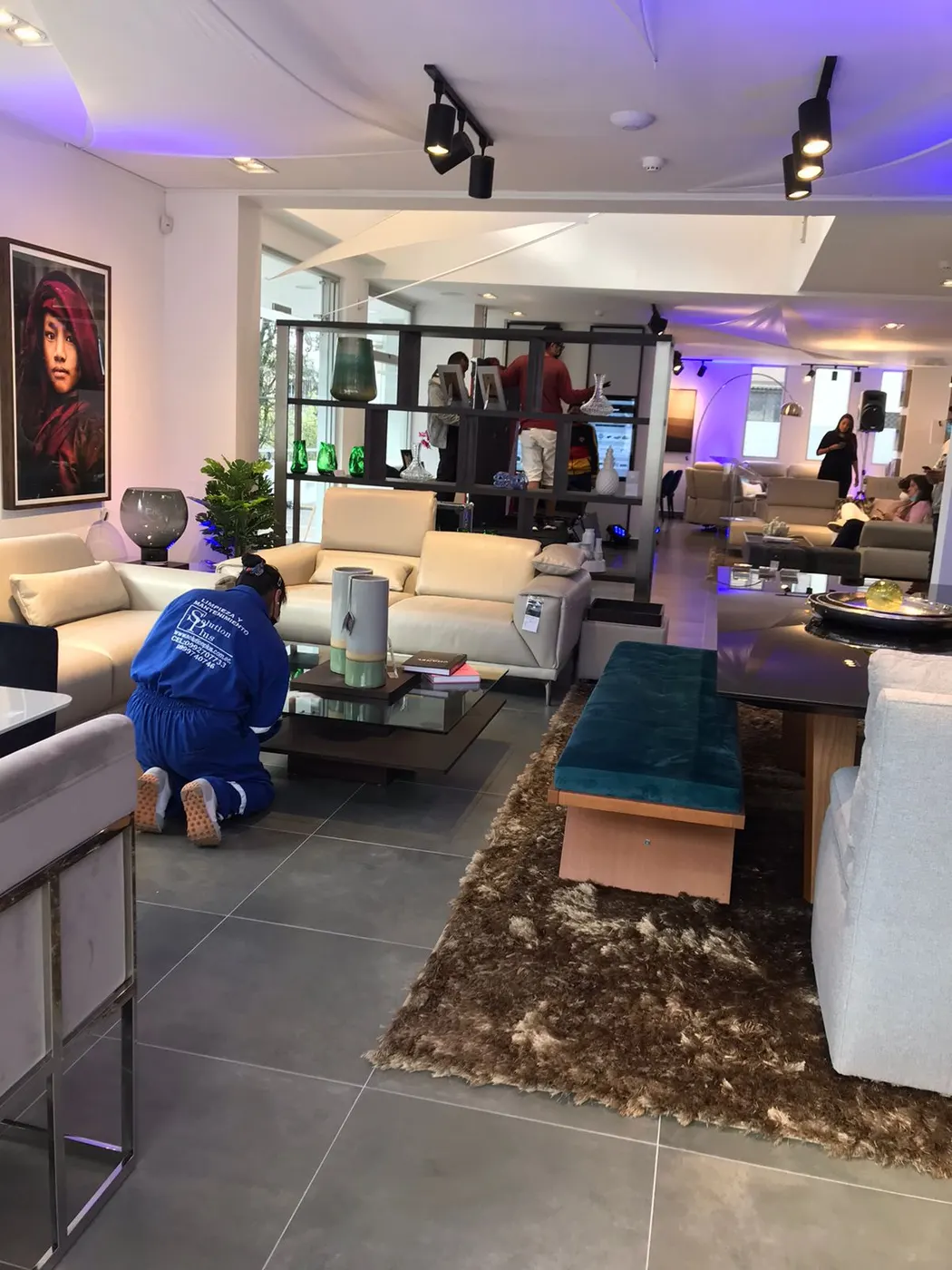 Trabajador de SolutionPlus limpiando en detalle una mesa de centro en un showroom de diseño